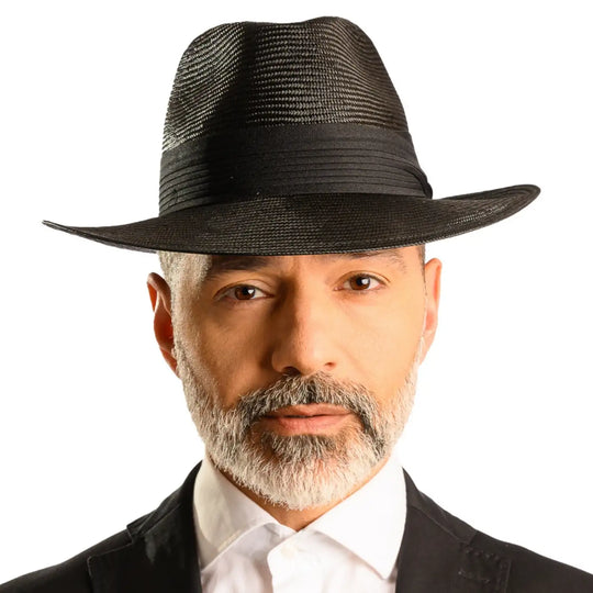 primo piano frontale di uomo con barba che indossa un cappello fedora elegante in parasisol color nero fatto da cappelleria primario nesti