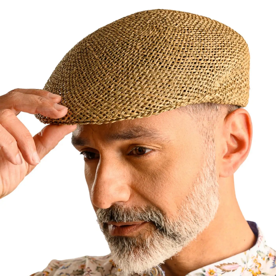 primo piano laterale inclinato di uomo con barba che indossa un coppola siciliana estiva di paglia color grezzo realizzato da cappelleria primario nesti