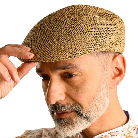 primo piano laterale inclinato di uomo con barba che indossa un coppola siciliana estiva di paglia color grezzo realizzato da cappelleria primario nesti