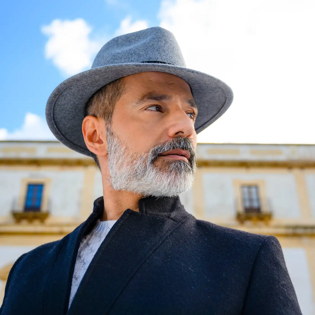 cappello fedora tesa media primario nesti grigio profilo ravvicinato di modello elegante con barba e sguardo interessante