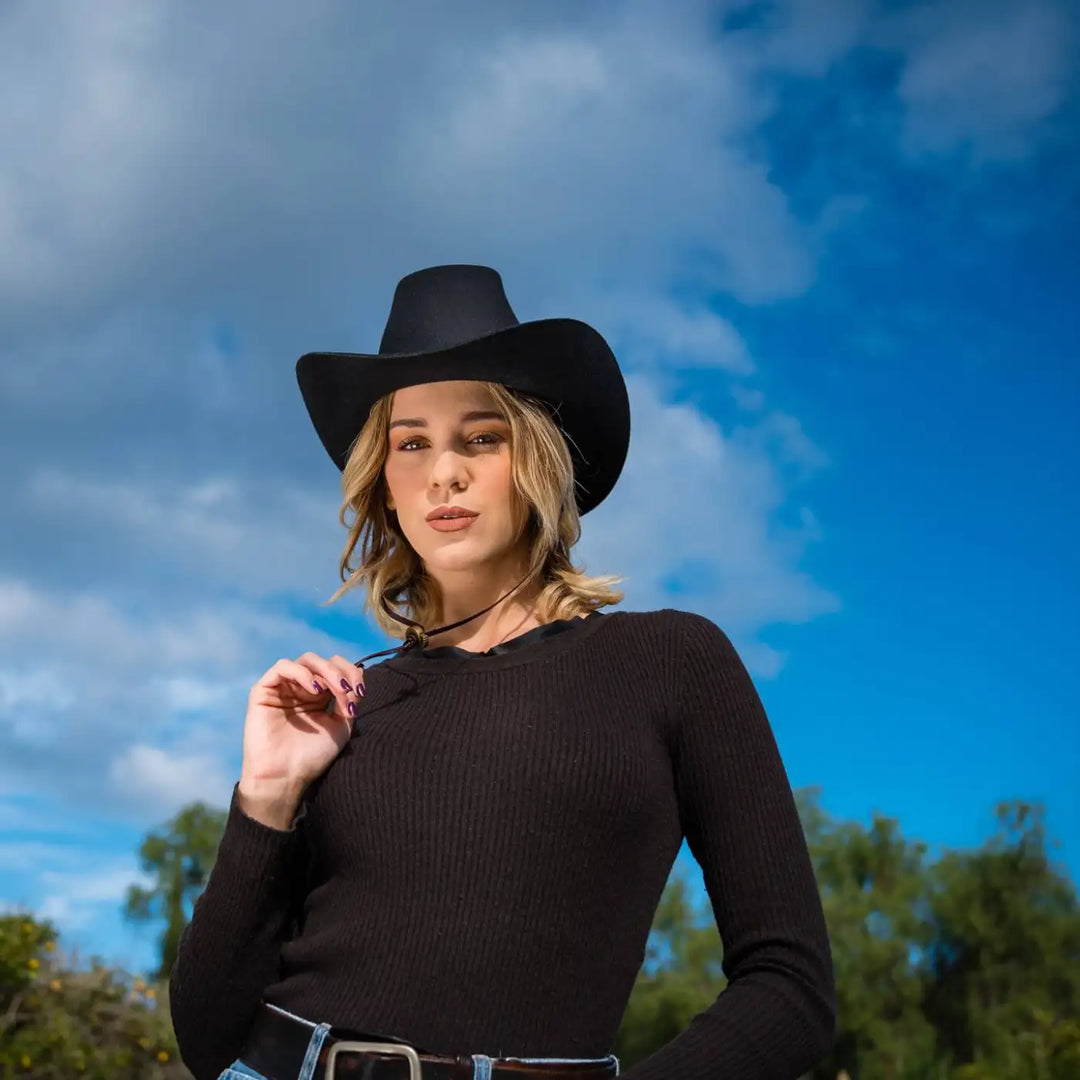 modella indossa cappello da cowboy in feltro di lana merinos antipioggia primario nesti nero nel suo look total black e sguardo intenso