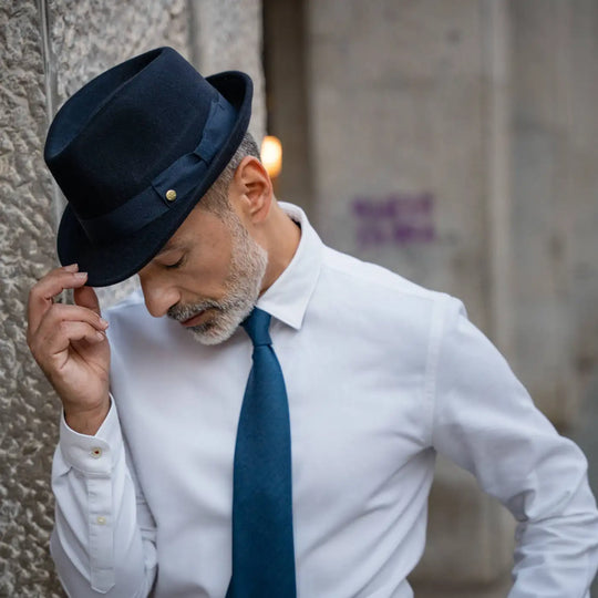 modello indossa trilby primario nesti lapin blu navy outfit formale minimalista gestualita naturale architettura storica