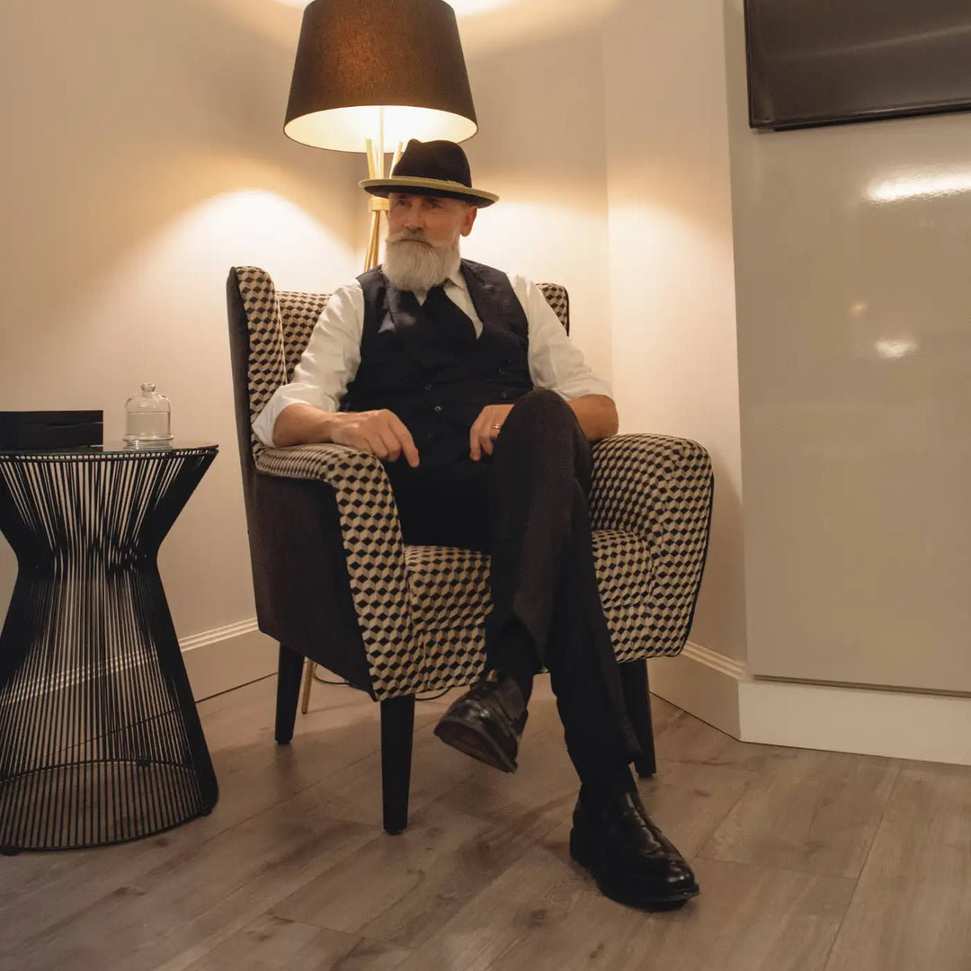 modello uomo distinto con cappello trilby tesa media primario nesti lapin blu in un ambientazione di un luxury hotel con design contemporaneo e luci soffuse