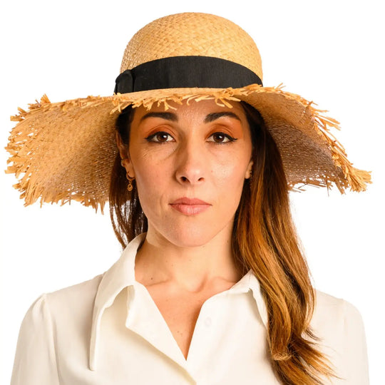 primo piano frontale di donna con capelli lunghi che indossa un cappello da sole a tesa larga in rafia color paglia fatto da cappelleria primario nesti