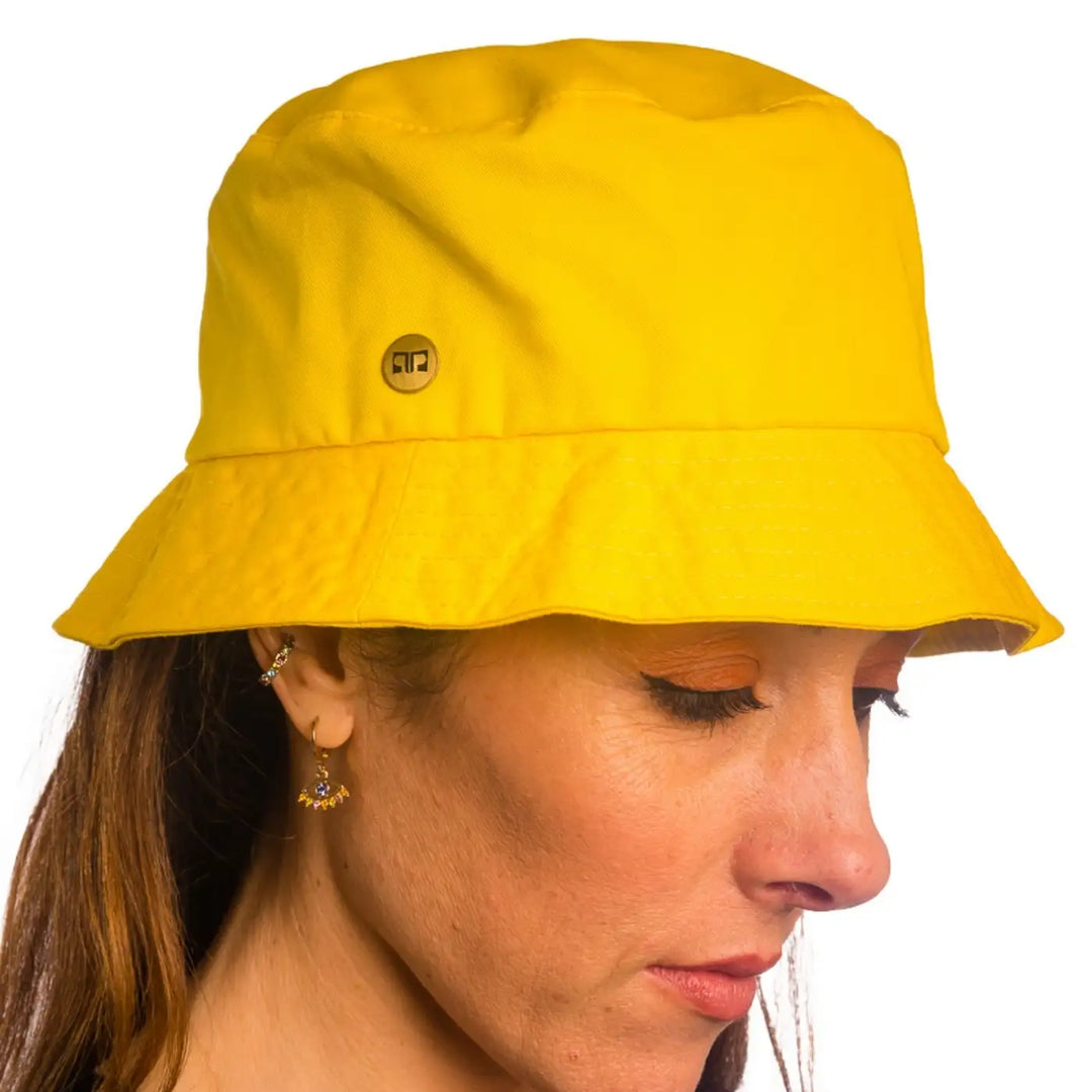 primo piano frontale inclinato di donna con capelli lunghi che indossa un cappello da pescatore sartoriale estivo color giallo fatto da primario nesti