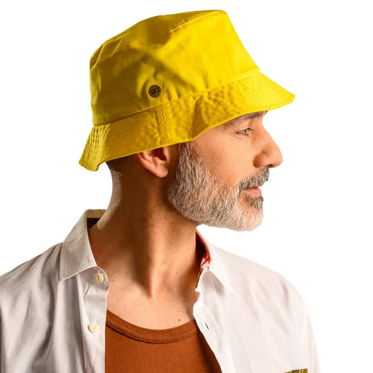 primo piano laterale di uomo con barba che indossa un cappello da pescatore sartoriale estivo color giallo realizzato da cappelleria primario nesti