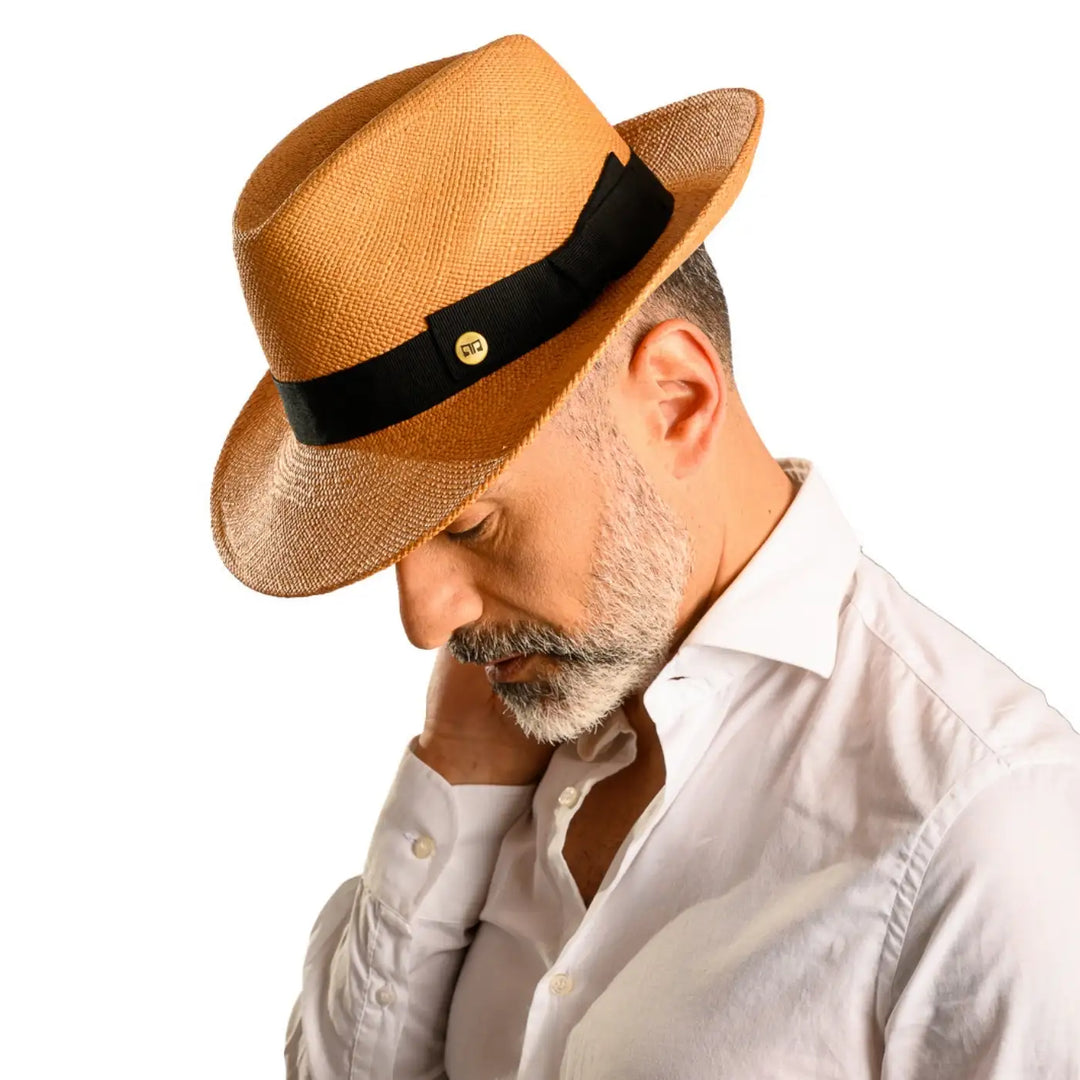 primo piano laterale inclinato di uomo con barba che indossa un cappello di panama in stile fedora color avana realizzato da cappelleria primario nesti