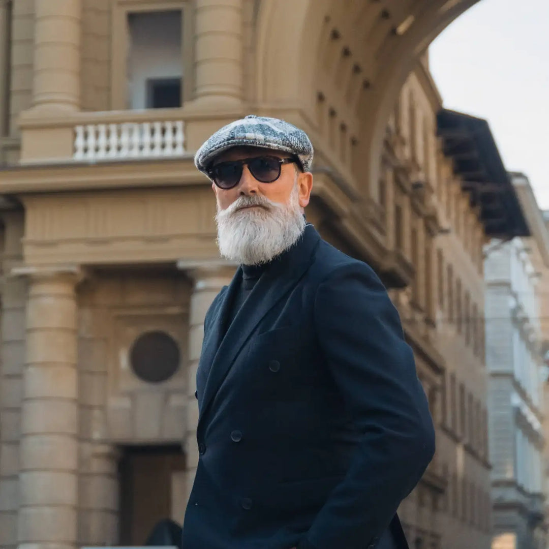 profilo raffinato di modello maturo con coppola peaky blinders di lana in fantasia chiara primario nesti colonnato classico sullo sfondo e stile sartoriale italiano