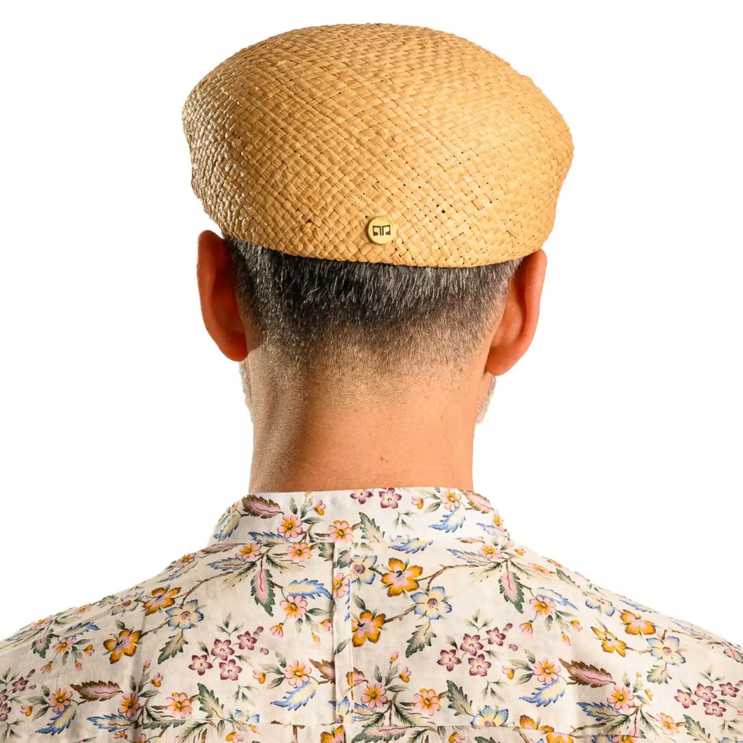 vista posteriore di un uomo con barba che indossa un coppola siciliana estiva in rafia color paglia fatto a mano da cappelleria primario nesti